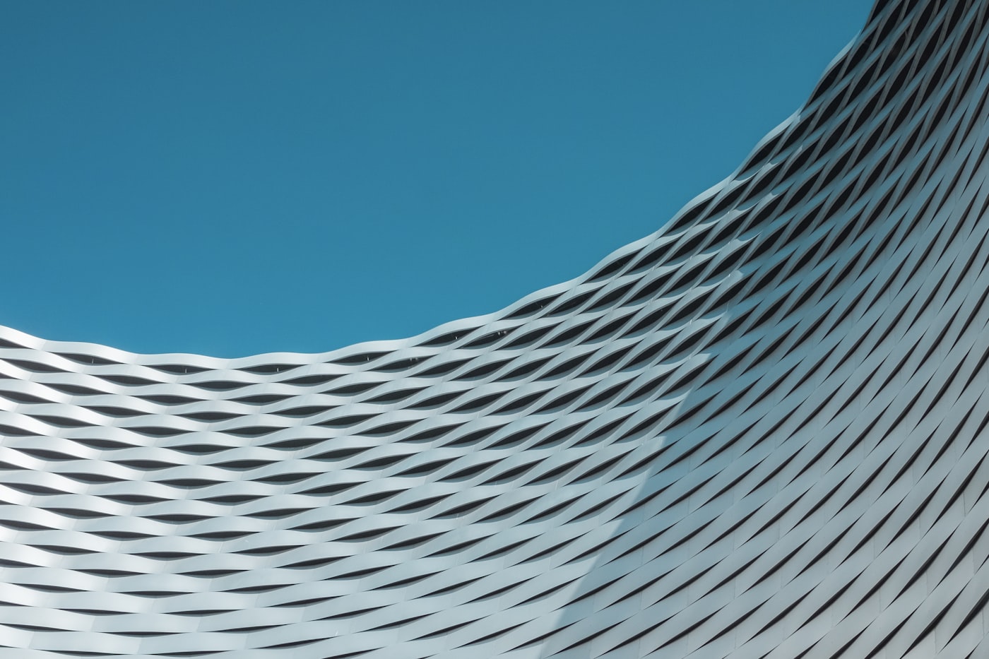 Curved white lattice facade, structure repeating at scale