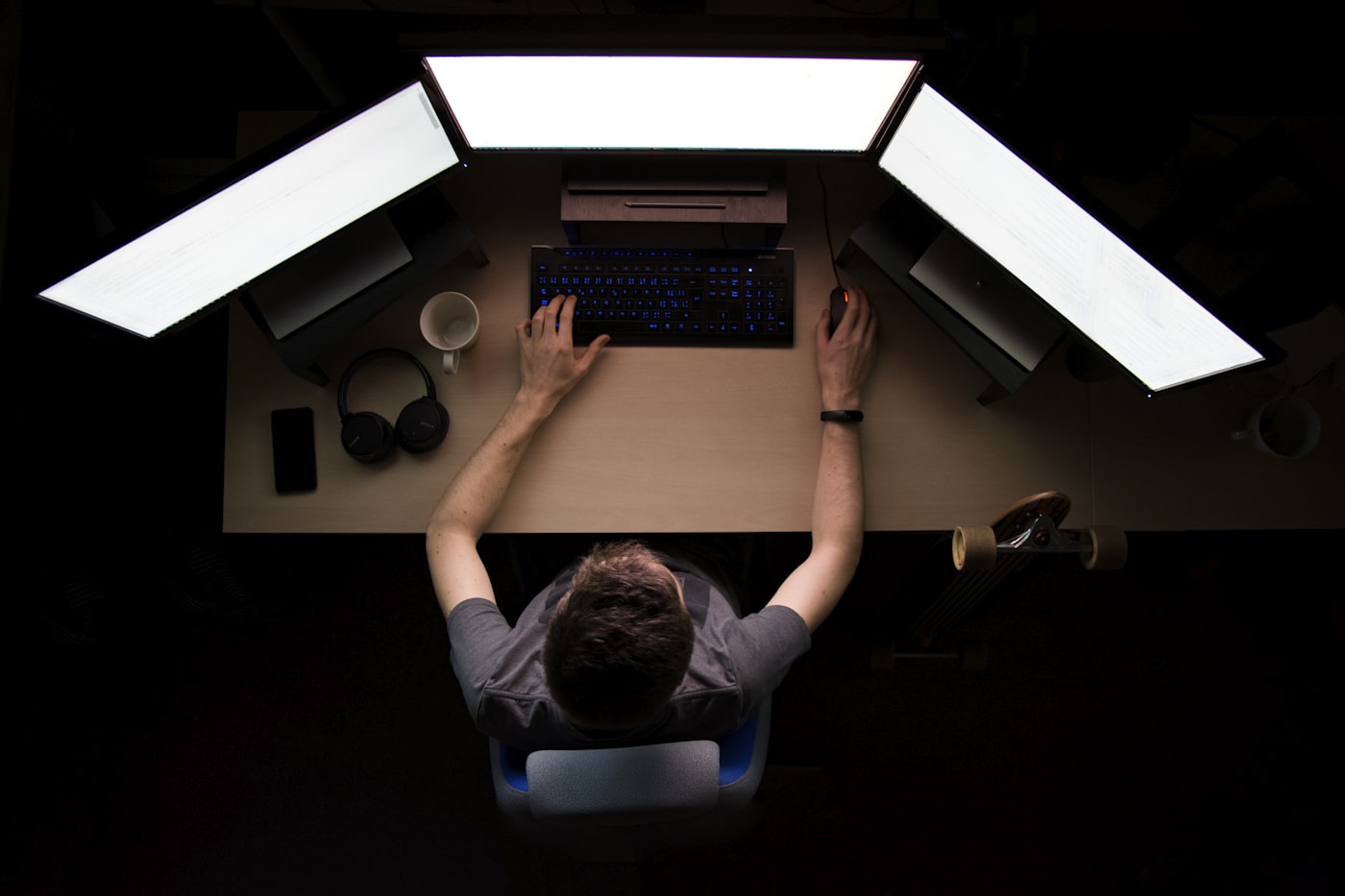 Developer working across three monitors in a dark room